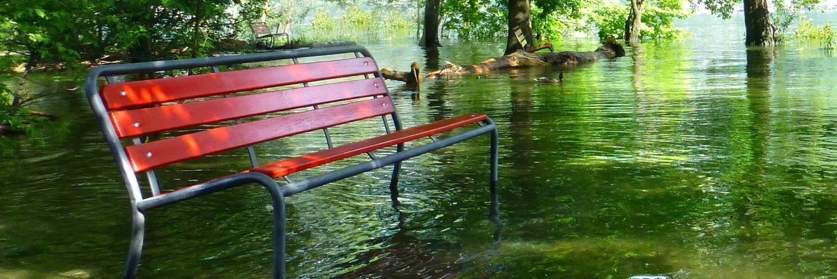 Rote Parkbank im Hochwasser stehend